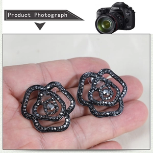 Detailed macro view of black rose stud earrings with rhinestones and hollow petals