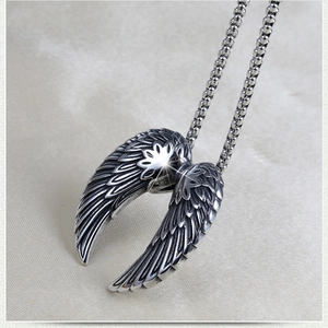 Detail of vintage silver angel wings pendant with intricate feather texture on ball chain