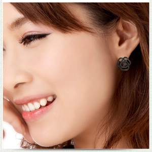 Close-up of black rose stud earrings with hollowed petal design on female model