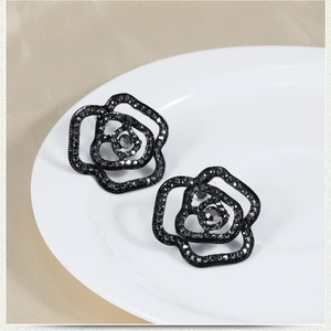 Elegant black rose stud earrings with rhinestones on a satin background
