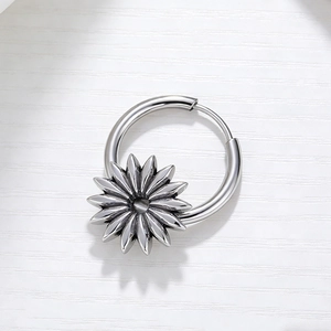 Vue macro de boucles d'oreilles tournesol en argent avec des pétales sur fond texturé