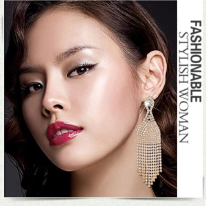 Close-up of golden tassel earrings with sparkling rhinestones worn by a model