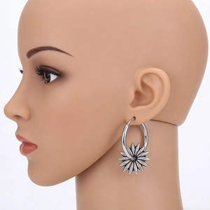 Détail de créoles argentées vintage avec pendentif fleur sur un mannequin