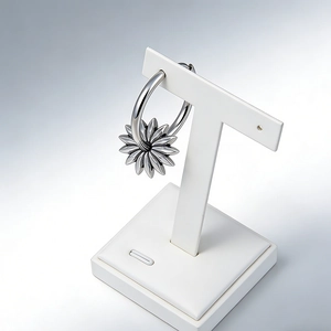 Détail des boucles d'oreilles fleur argentée sur un support à bijoux en T