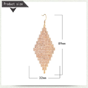 Détail de la taille de longues boucles d'oreilles losange dorées avec pavage de cristaux