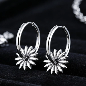 Détail macro de créoles fleurs argentées avec pétales gravés sur velours noir