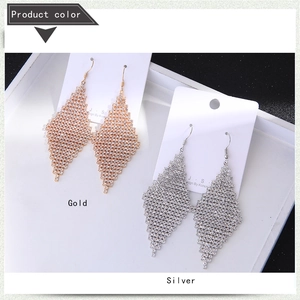 Détail de boucles d'oreilles losange en or et argent serties de strass scintillants