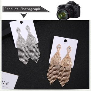 Detail of silver and gold tassel earrings with rhinestone fringe on black background