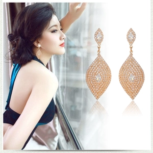 Detailed view of elegant gold leaf tassel earrings with sparkling rhinestones on a female model