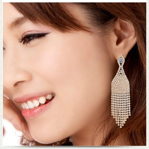 Detailed close-up of long gold fringe tassel earrings with shimmering crystals on a model