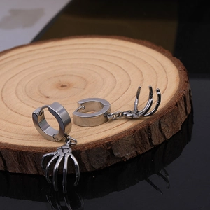 Detailed close-up of gothic stainless steel skull hand earrings on a wooden display