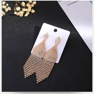 Close-up of sparkling gold tassel earrings with full crystal paving on black background