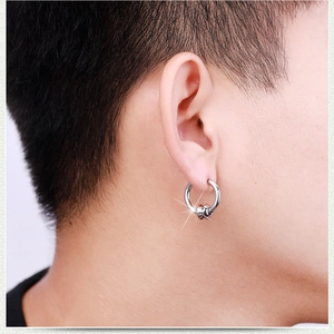 Detail of silver stainless steel hoop earring with movable bead on male ear lobe