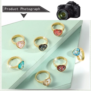 Macro view of gold plated heart rings with colorful gemstone inlay on display stand