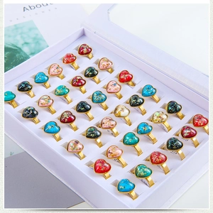 Golden heart rings set with colorful stones and resin in a display box for women