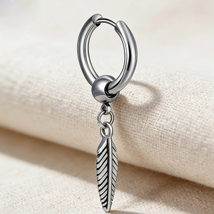 Gros plan d'une créole vintage en acier titane avec un pendentif feuille détaillé