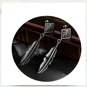 Detail of vintage silver feather pendant earrings on a deep red antique book