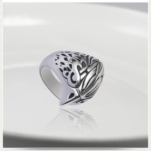 Macro view of men's skull ring featuring intricate wing patterns in polished steel