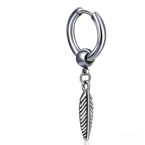 Détail d'une boucle d'oreille punk vintage en acier titane avec un pendentif plume ciselé