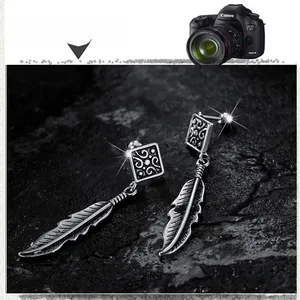 Close-up of vintage silver feather dangle earrings with intricate carved patterns on rock