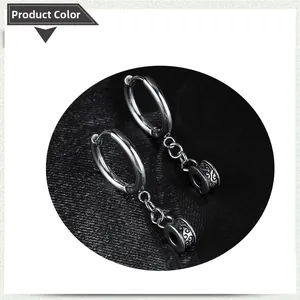 Close-up of stainless steel hoop earrings with engraved cross and chain details