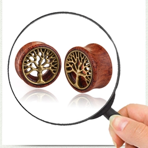Macro detail of wooden ear gauges featuring bronze tree of life metal inlay design