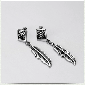 Detail of vintage silver feather earrings with intricate floral relief on square studs