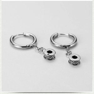 Macro shot of stainless steel hoop earring featuring a scroll pattern cylinder pendant