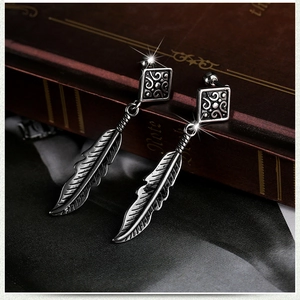 Vintage silver stainless steel cross feather drop earrings on dark silk background