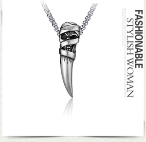 Gros plan du pendentif crâne momie et dent de loup punk en acier inoxydable poli