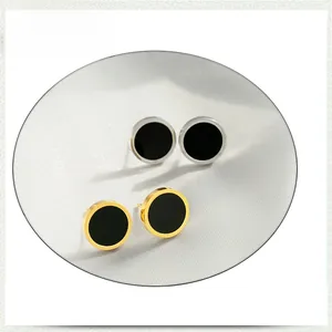 Gros plan de boucles d'oreilles haltères en acier doré et argenté avec insert noir
