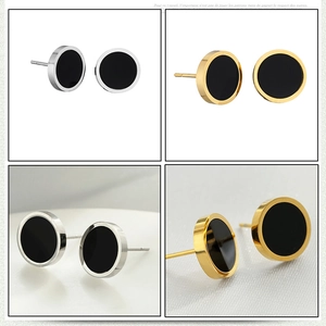Gros plan de boucles d'oreilles haltères noires en acier inoxydable argenté et doré