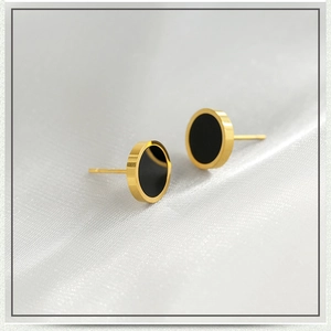 Détail de boucles d'oreilles rondes noires minimalistes avec bordure en acier doré