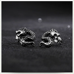 Symmetric pair of stainless steel dragon earrings with detailed scales on black background