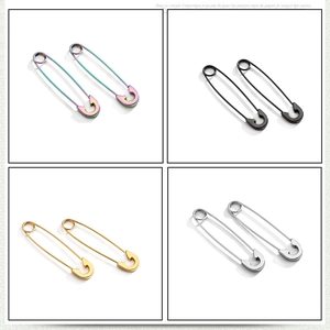 Detail view of safety pin earrings in silver, gold, black, and rainbow metallic finishes