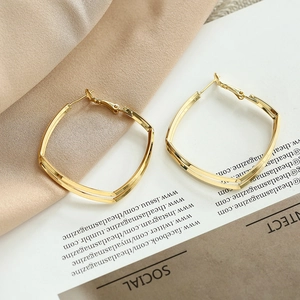 Elegant gold layered hoop earrings on white magazine and satin fabric with soft light