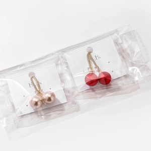 Détail de boucles d'oreilles cerises en perles rouges et champagne avec crochets dorés