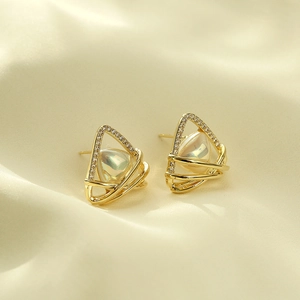 Macro shot of gold triangular earrings with pavé crystals and iridescent inlay