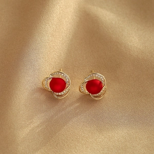 Boucles d'oreilles spirales dorées avec perles rouges et zircons sur soie champagne