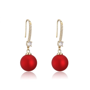 Détail de boucles d'oreilles pendantes rouges avec plaqué or et accents de zircon blanc
