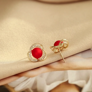 Boucles d'oreilles fleur dorée avec perle rouge mate et cristaux sur tissu satiné