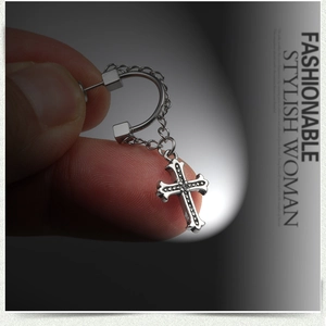 Macro shot of silver stainless steel earring with hanging cross and black micro-zircons