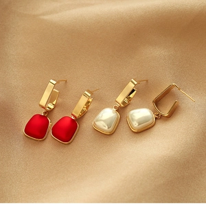 Elegant gold geometric tassel earrings with red and pearlescent pendants on silk