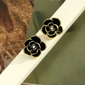 Detail of vintage camellia stud earrings with black enamel and sparkling center crystal