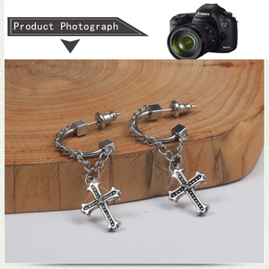 Detailed view of stainless steel cross drop earrings on a wooden display stand