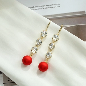 Boucles d'oreilles pendantes dorées avec perles rouges et détails en cristal