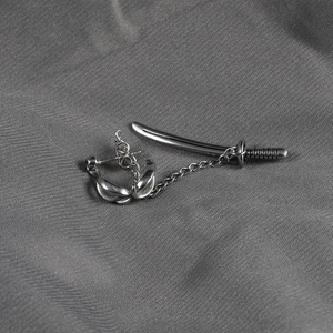 Macro shot of silver katana sword earrings with chain link and punk style metal textures