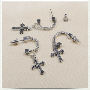 Close-up of silver stainless steel cross earrings with beaded edges on fabric