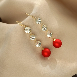 Boucles d'oreilles pendantes dorées avec cristaux verticaux et perles rouges sur satin
