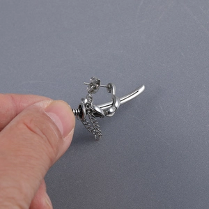 Macro shot of silver samurai sword drop earring with metal chain in punk gothic style